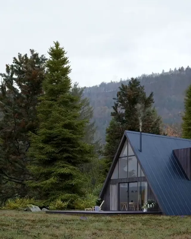 The front of an A-frame cabin, glass from the deck to the peak, lit from inside