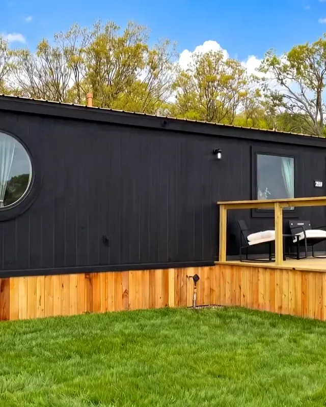 Inside the Family Cabin: the open living room, dining table and kitchen, with the window wall onto the deck
